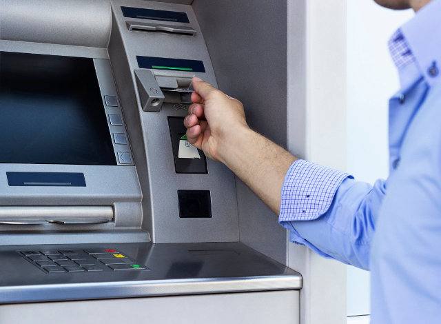 Hand of man with credit card, using a ATM